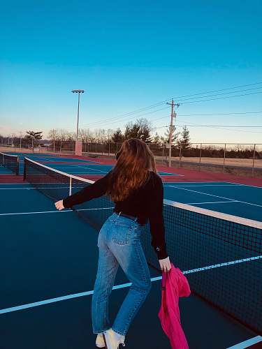 tennis court woman standing beside tennis net under clear blue sky person